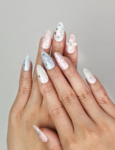 Hand wearing Naillover Starry Sweet Dream handmade press on nails in pearlescent pink, blue, and white with 3D stars and pearls.